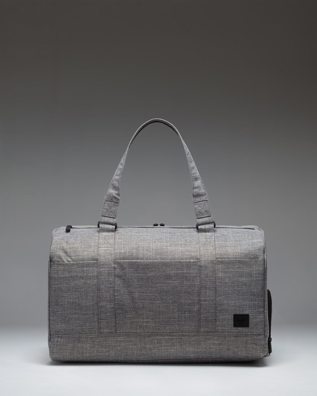 Herschel Novel Duffle Tech bag in Raven Crosshatch grey, showing a side view of the tech compartments and handles.