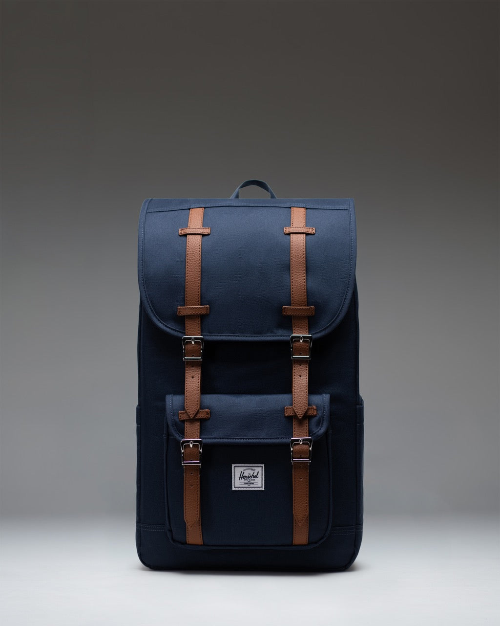Navy blue Herschel Little America Backpack with classic front pocket and brown fastening straps.