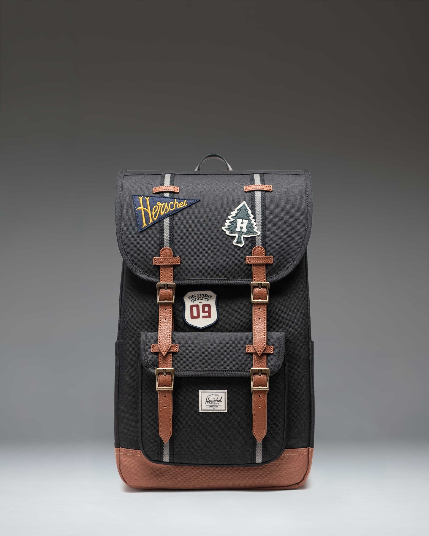 Herschel Little America Backpack in Patches Black, showing the front view with dual rubber straps and embroidered patch details.