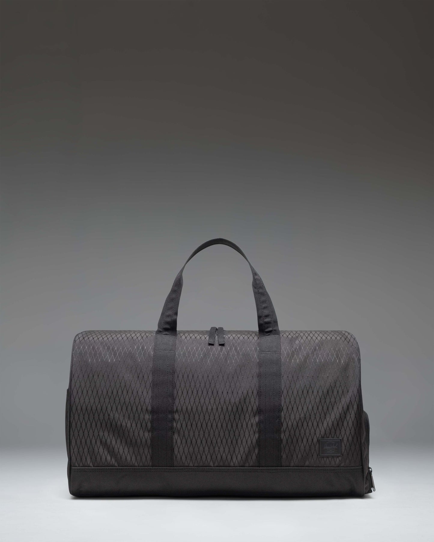 Herschel Novel Duffle bag in Black Diamond/Black color, showing a side view of the clean, textured fabric design with carry handles and shoulder strap.