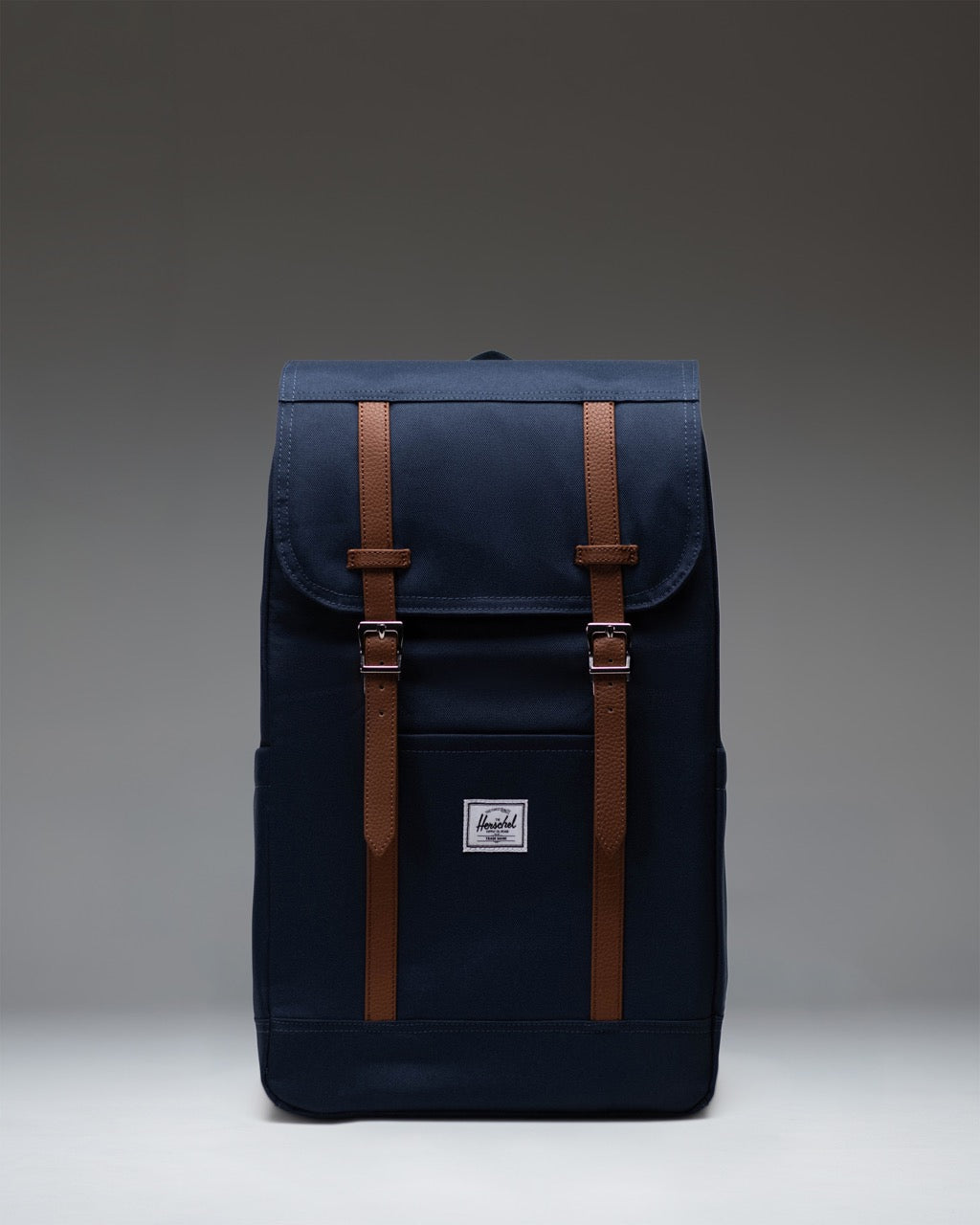 Herschel Retreat Backpack in navy blue, featuring a classic cinch-top design with dual brown strap closures and a front storage sleeve.