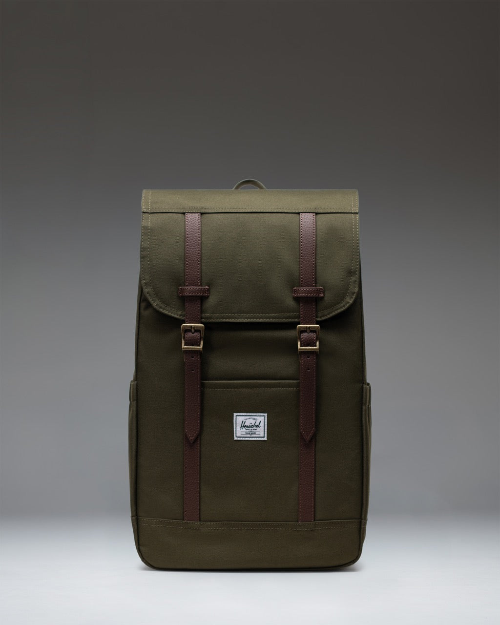 Herschel Retreat Backpack in Ivy Green with brown strap details and a classic woven label on the front.