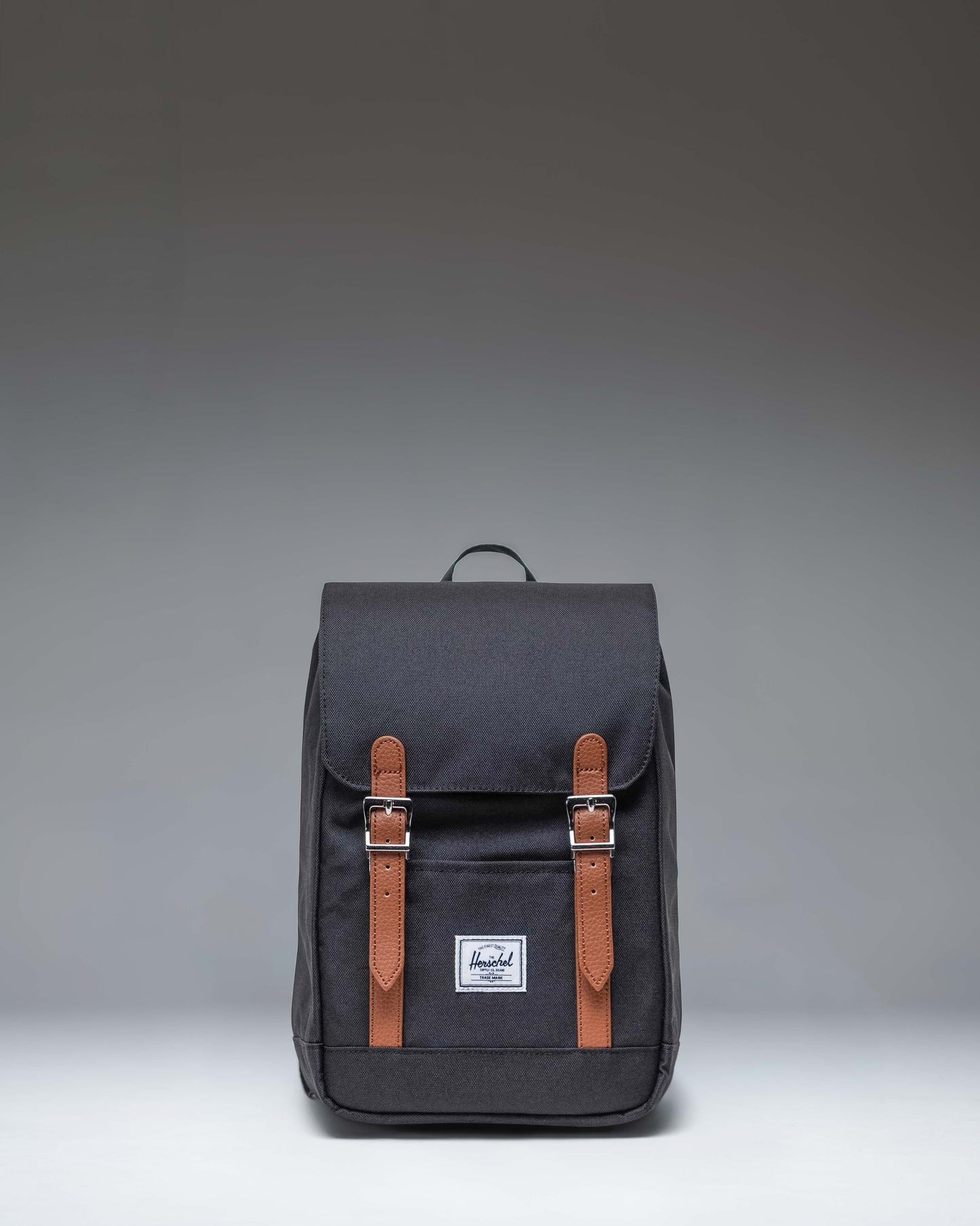 Herschel Retreat Mini Backpack in Black. Front view showcasing its classic design with a top handle, single strap closure, and front storage sleeve.