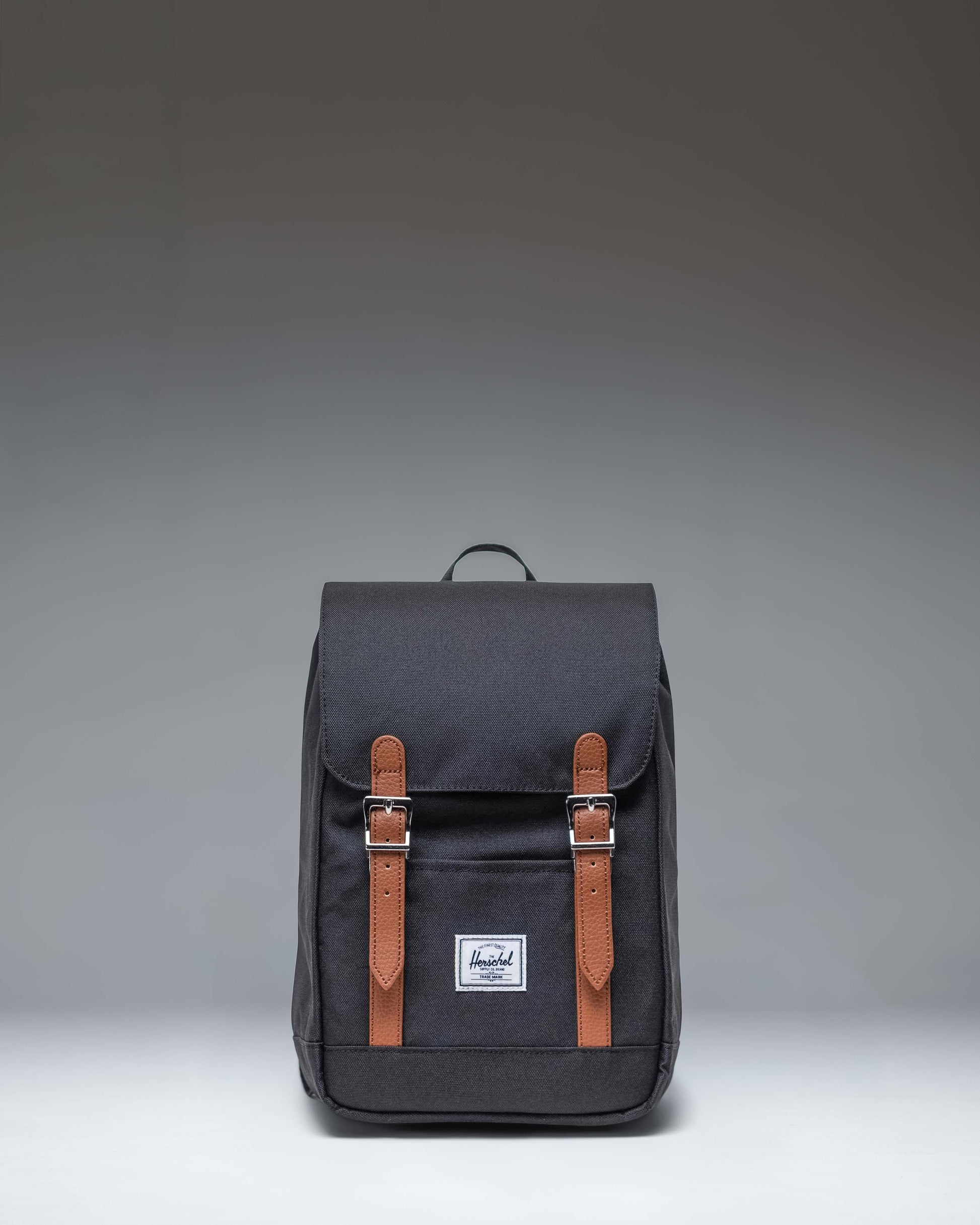 Herschel Retreat Mini Backpack in Black. Front view showcasing its classic design with a top handle, single strap closure, and front storage sleeve.