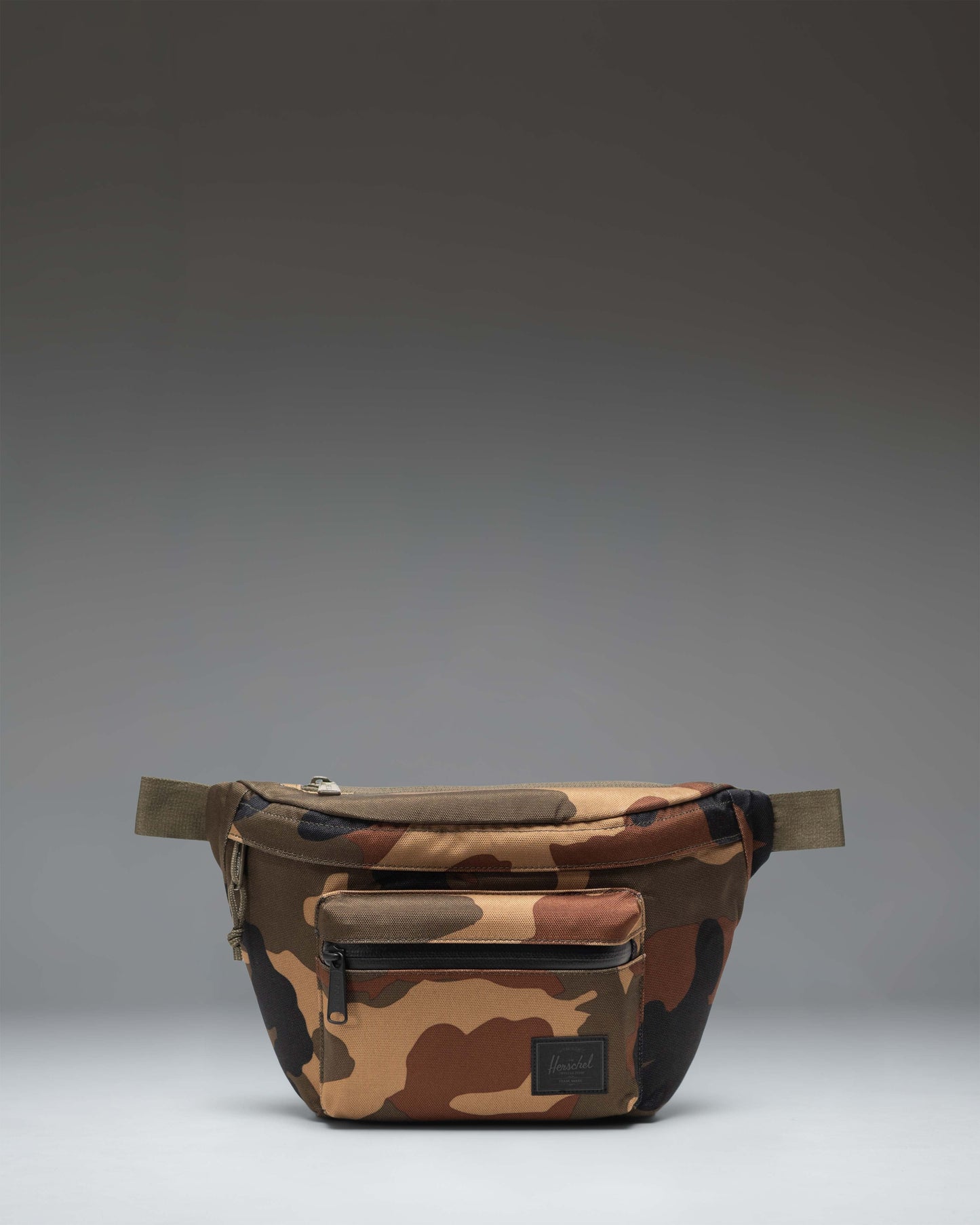 Herschel Supply Co Pop Quiz Hip Pack in Woodland Camo featuring a front zippered pocket and adjustable webbing strap.