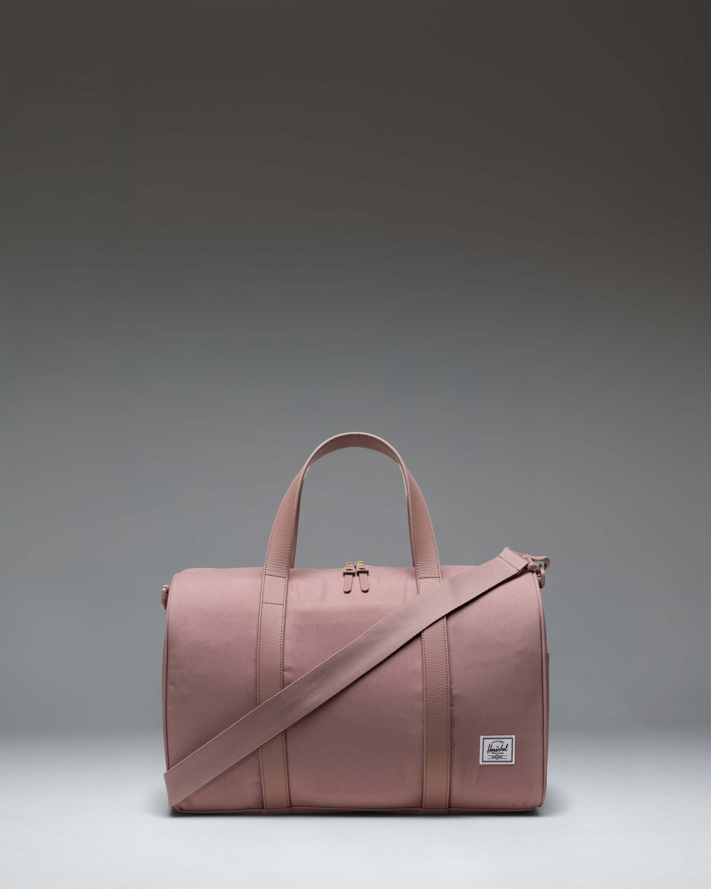 Herschel Supply Co. Novel Carry On Duffle bag in Ash Rose, a soft pink duffel with top handles and a removable shoulder strap.