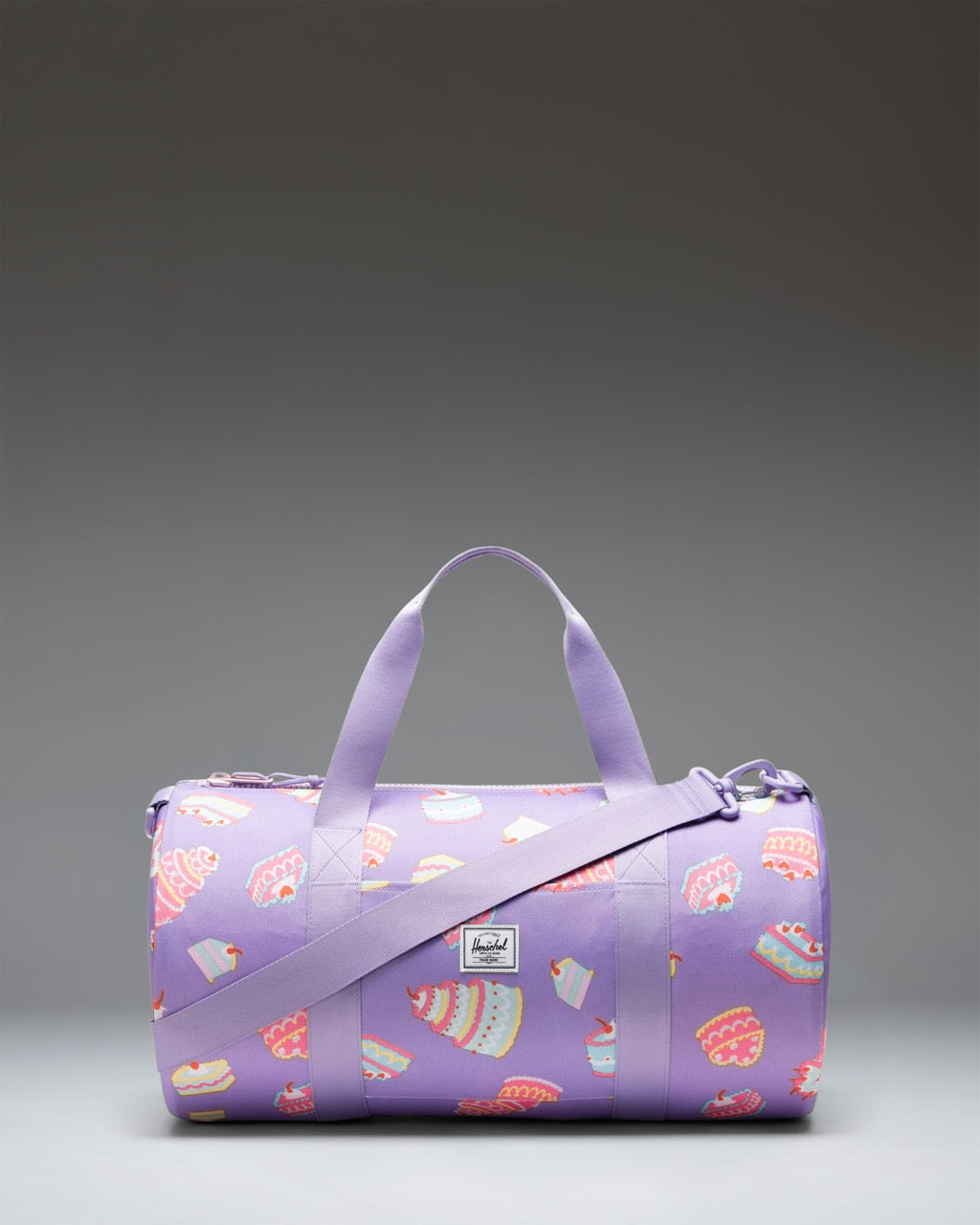 Herschel Classic Duffle Little Herschel in Cakes colorway, a pink kids' duffle bag featuring a colorful cake pattern.