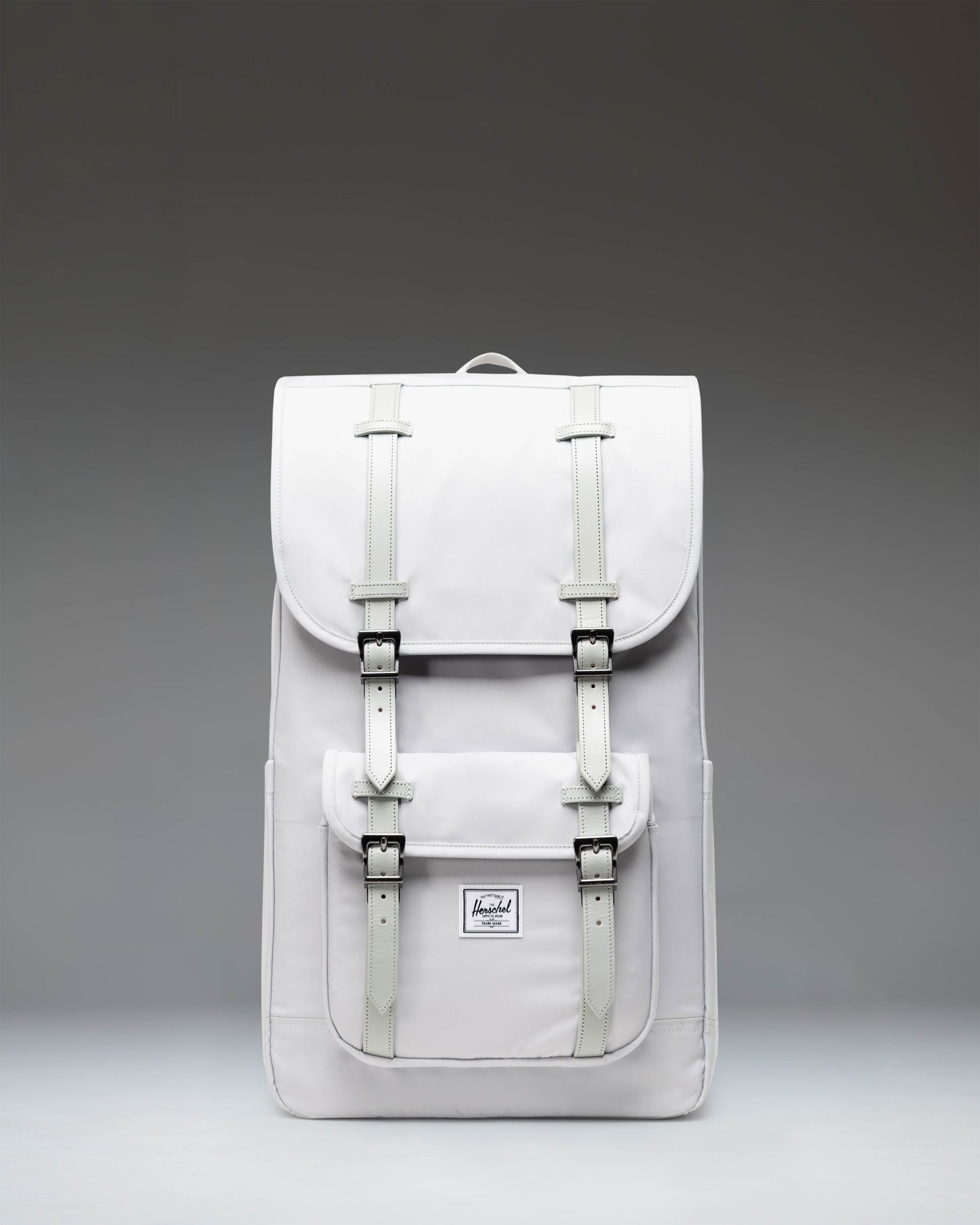 Herschel Little America Backpack in Metal grey, featuring a front pocket with strap details, a top flap closure, and padded shoulder straps.
