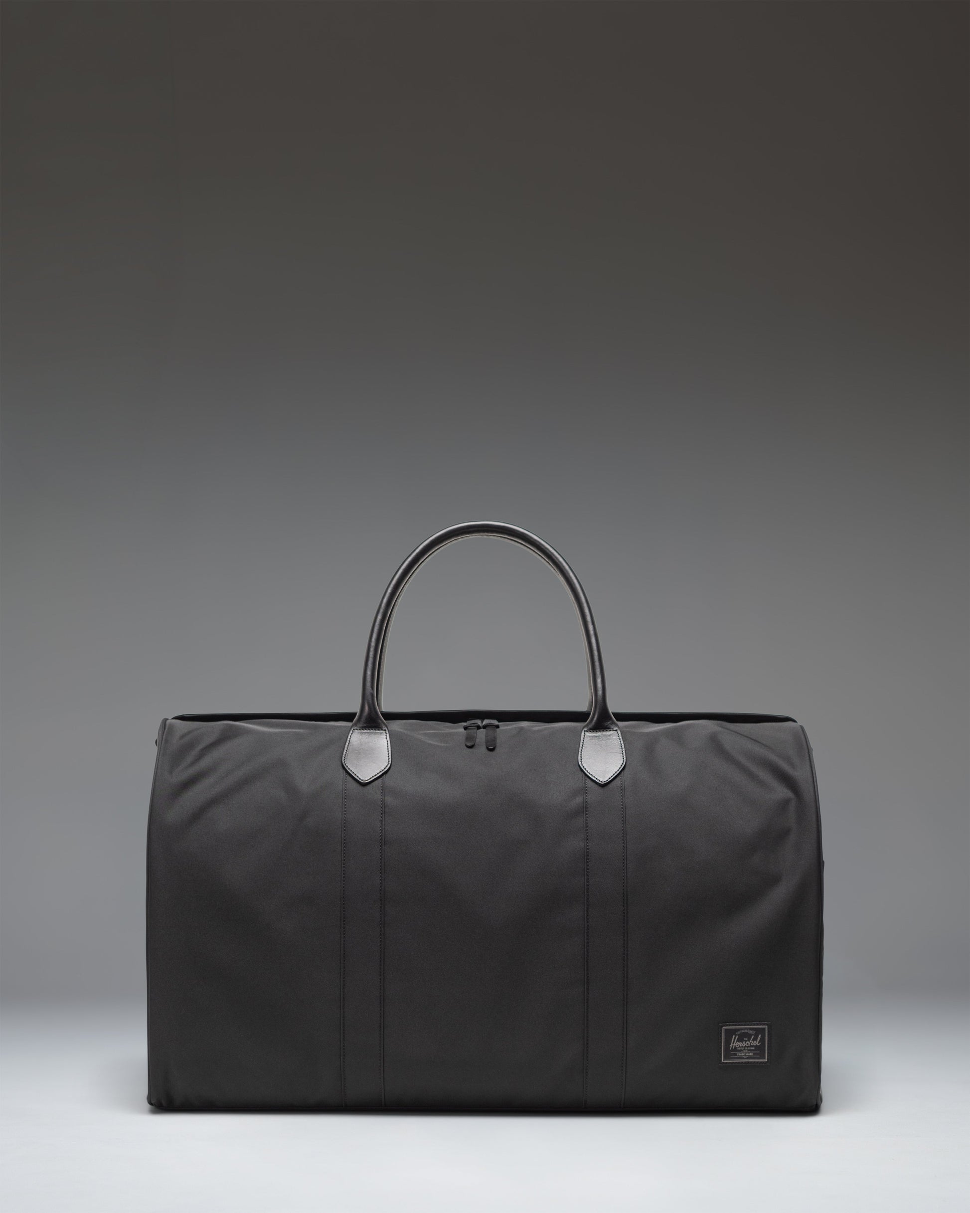 Herschel Novel Duffle bag in black, showing the clean classic design, durable handles, and signature shoe compartment.