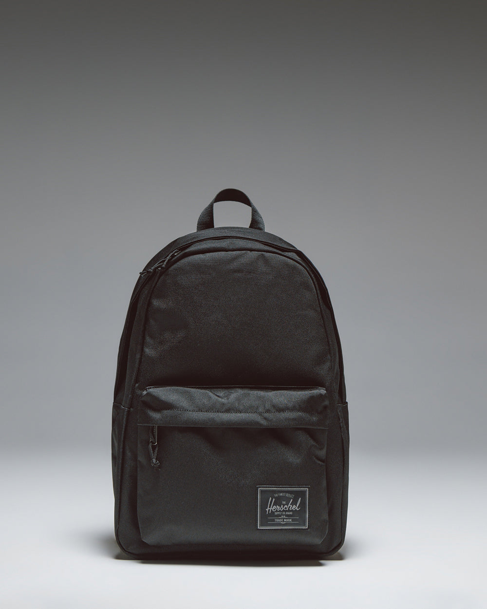 Herschel Classic XL Backpack in Black Tonal, shown from the front with a clean, classic design featuring a zippered front pocket and shoulder straps.