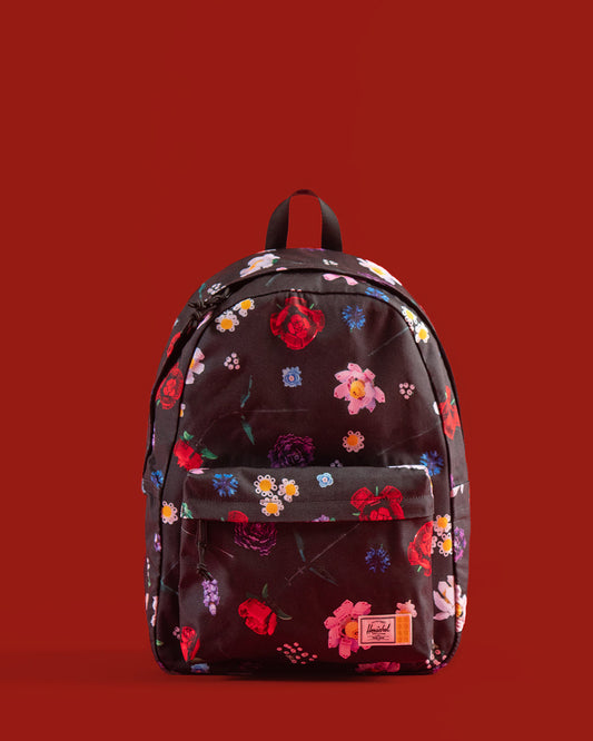 Herschel Supply Co. LEGO Classic Backpack in Falling Florals print, showing a navy blue bag covered in a colorful floral pattern with Lego brick details.