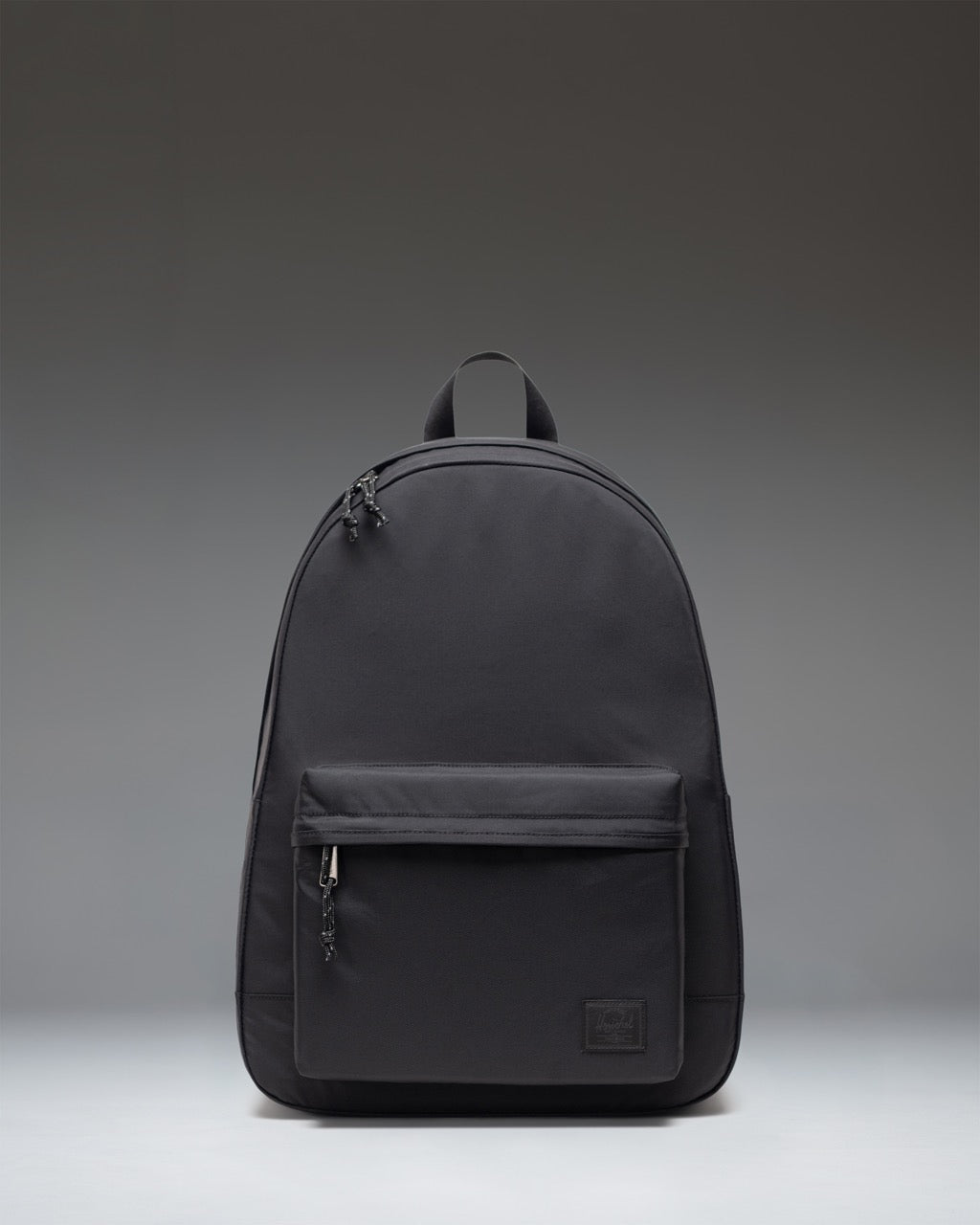 Front view of the Herschel Classic XL Backpack in black, featuring a zippered main compartment and front pocket with the signature woven label.