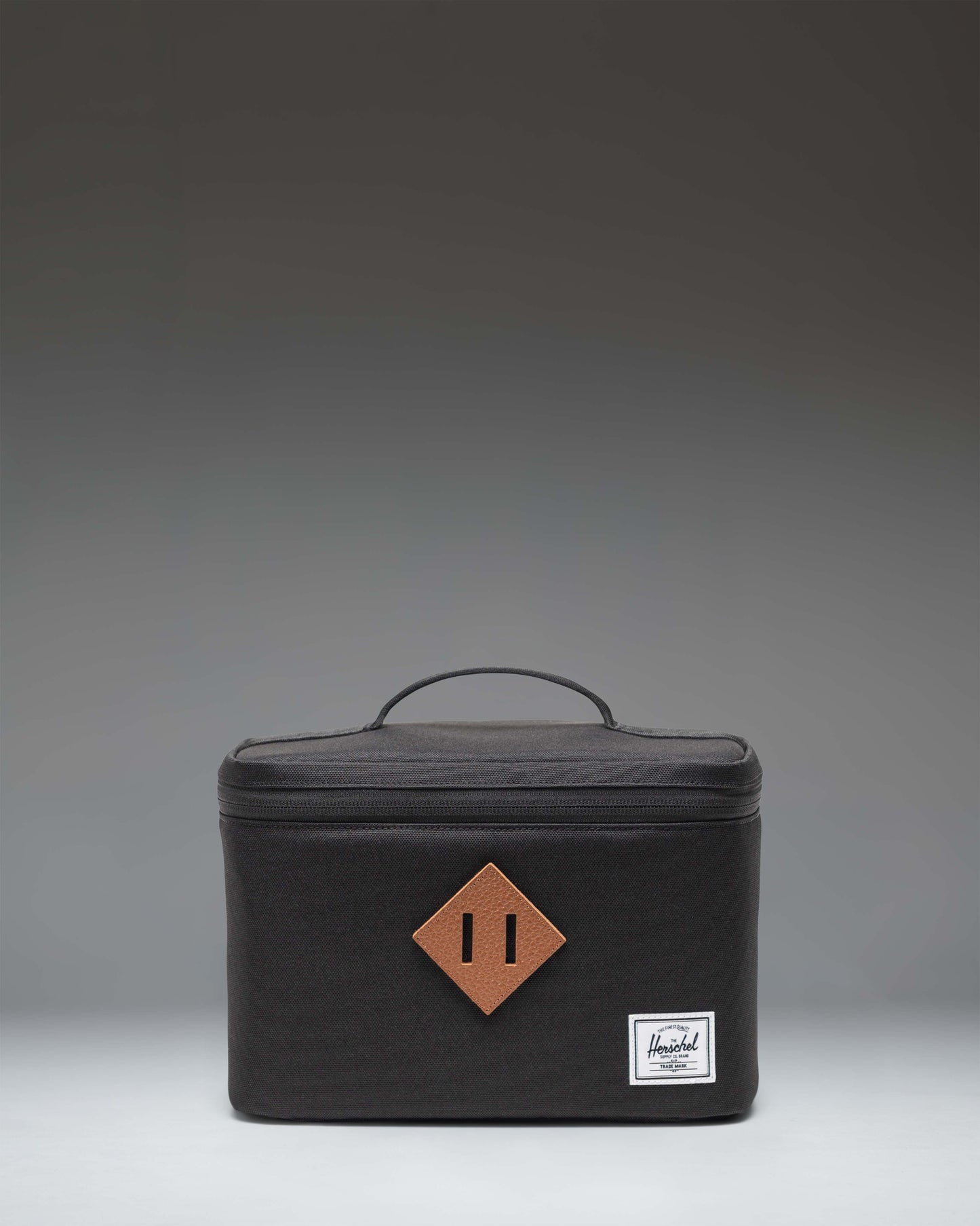 Herschel Heritage Lunch Box in black, showing the front view with the signature diamond accent and woven label.