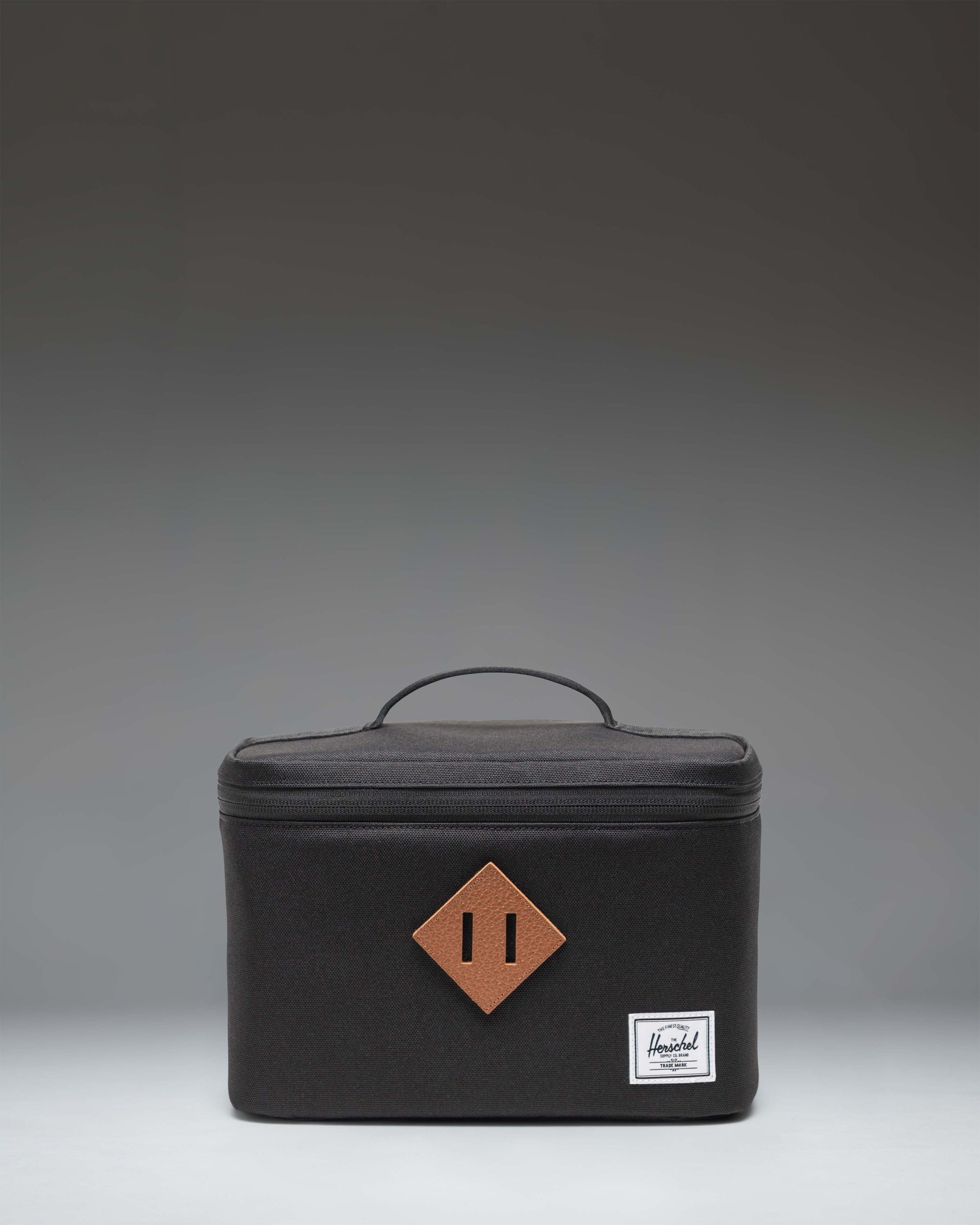 Herschel Heritage Lunch Box in black, showing the front view with the signature diamond accent and woven label.