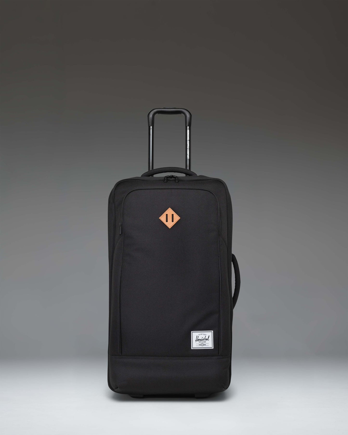 Herschel Heritage Softshell Medium Luggage in black, showing an oversized view of the front exterior fabric, zipper, and subtle tonal branding.