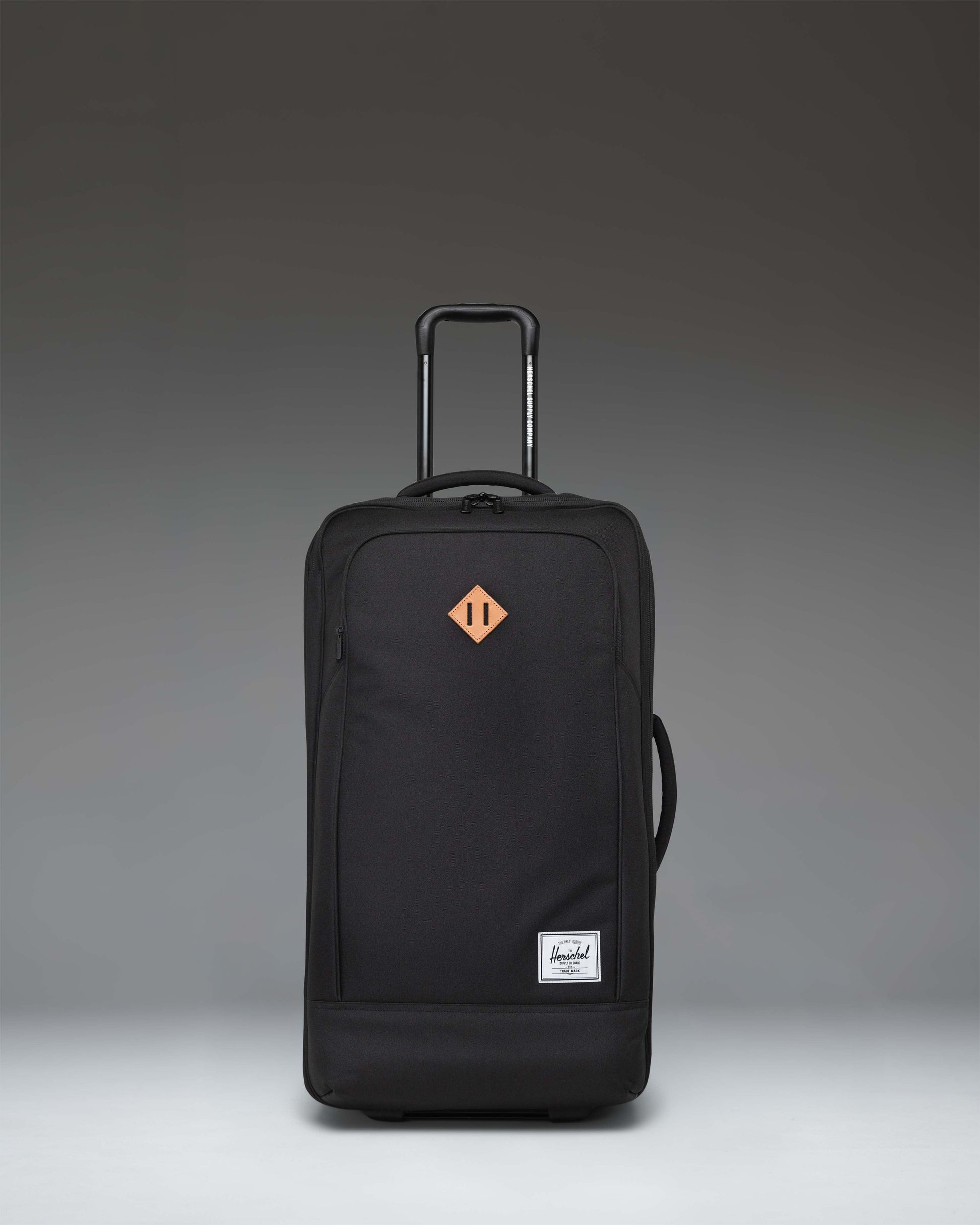 Herschel Heritage Softshell Medium Luggage in black, showing an oversized view of the front exterior fabric, zipper, and subtle tonal branding.