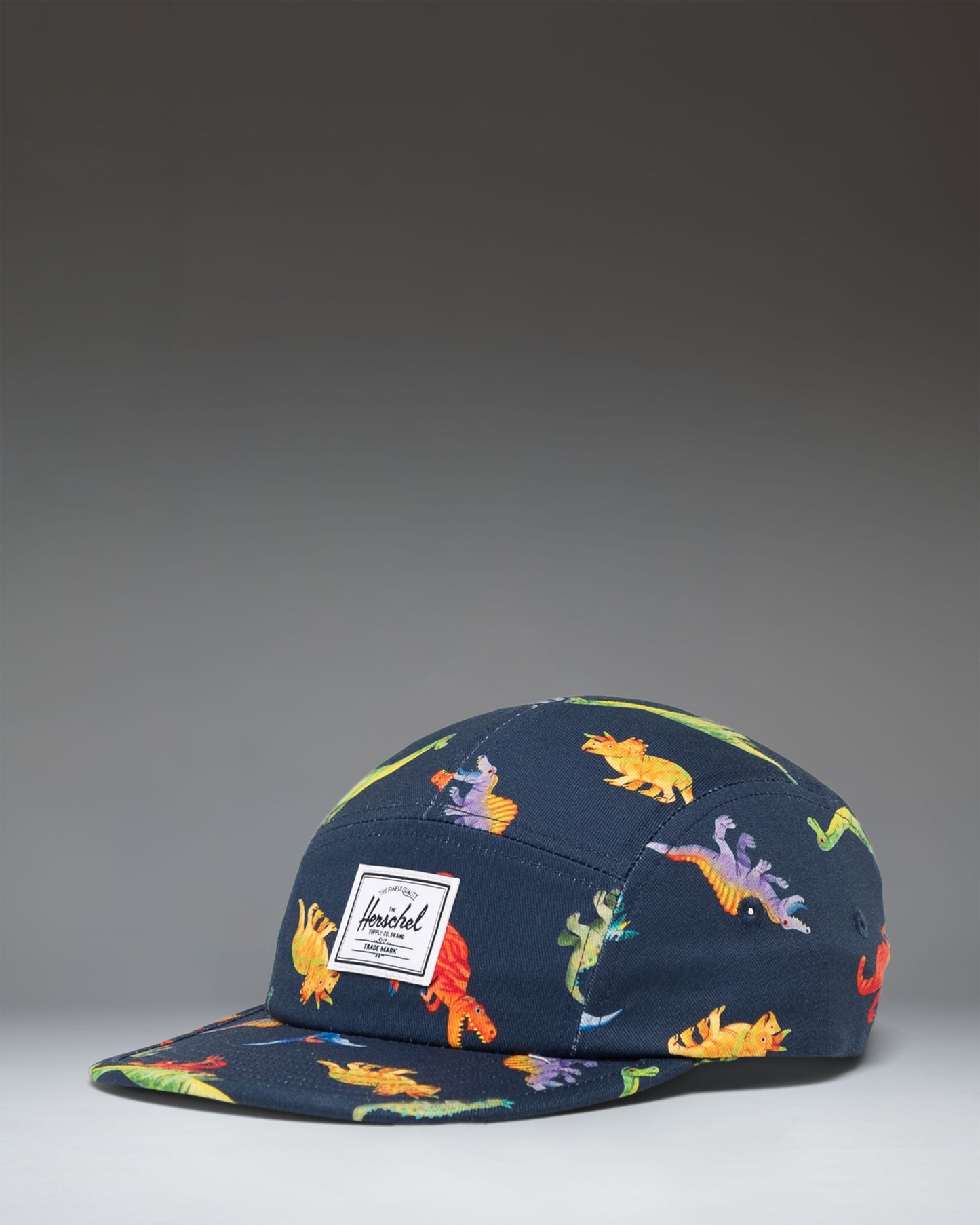 Herschel Supply Co. Glendale Kids Cap in Water Colour Dinosaurs Darkest Navy, featuring a colorful dinosaur pattern on a dark navy background.