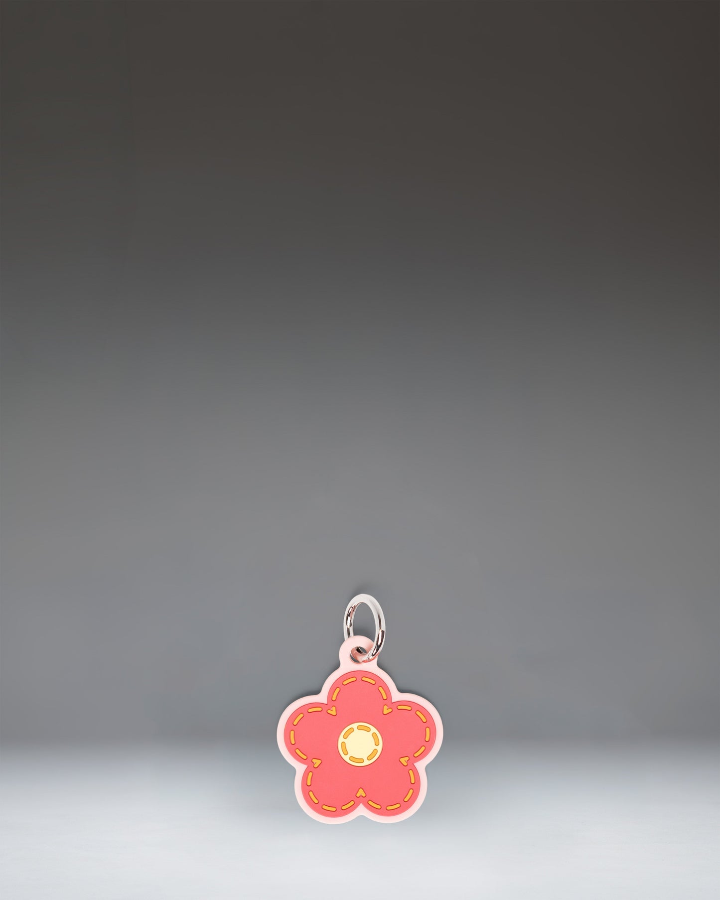 Herschel Daisy Bag Charm in Pink Daisy, featuring a stylized pink daisy flower design with a central yellow disc and attached metal hardware.