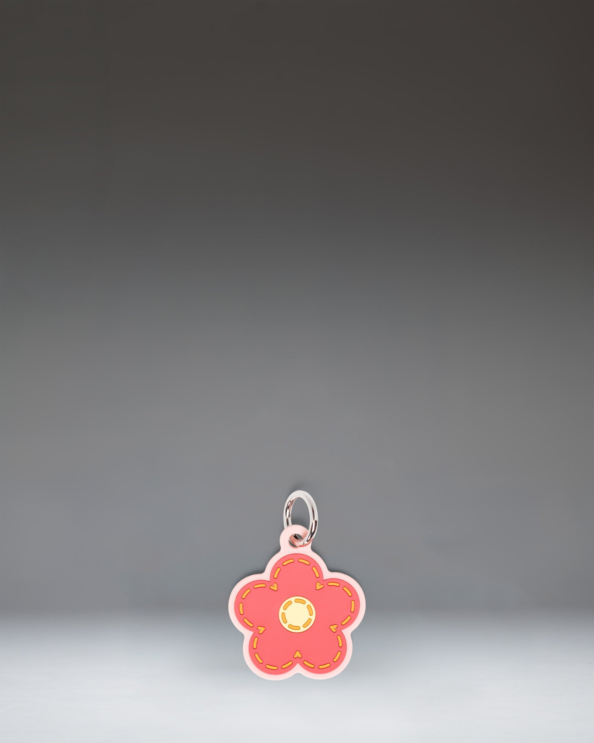 Herschel Daisy Bag Charm in Pink Daisy, featuring a stylized pink daisy flower design with a central yellow disc and attached metal hardware.